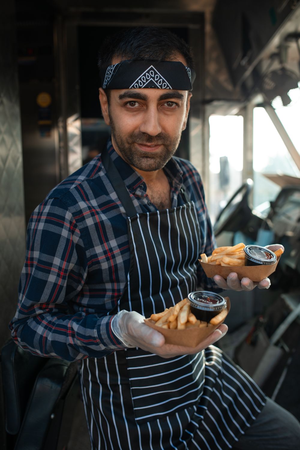 Dueño de un local gastronómico sosteniendo dos pedidos listos para entregar